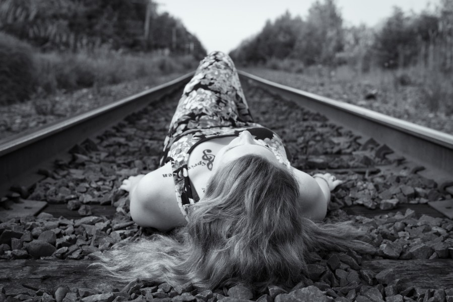 woman lying down on railroad track